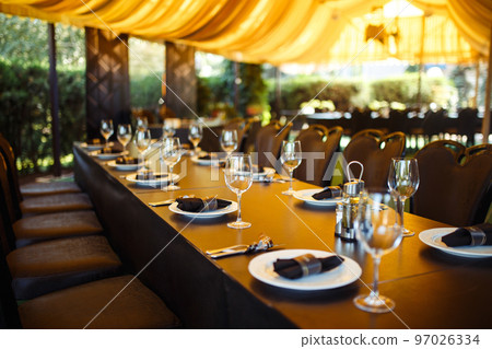 Sparkling glassware stands on long table prepared for wedding dinner. Sparkling glassware stands on long table prepared for wedding dinner. 97026334