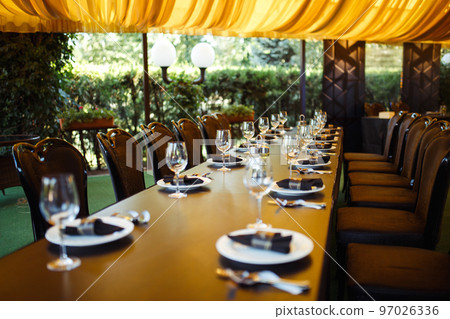 Sparkling glassware stands on long table prepared for wedding dinner. Sparkling glassware stands on long table prepared for wedding dinner. 97026336
