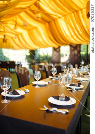Sparkling glassware stands on long table prepared for wedding dinner. Sparkling glassware stands on long table prepared for wedding dinner. 97026337