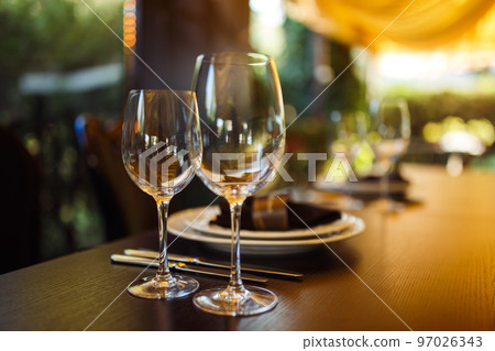 Sparkling glassware stands on long table prepared for wedding dinner. Sparkling glassware stands on long table prepared for wedding dinner. 97026343