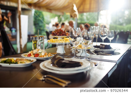 Sparkling glassware stands on long table prepared for wedding dinner. Sparkling glassware stands on long table prepared for wedding dinner. 97026344