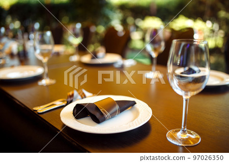Sparkling glassware stands on long table prepared for wedding dinner. Sparkling glassware stands on long table prepared for wedding dinner. 97026350