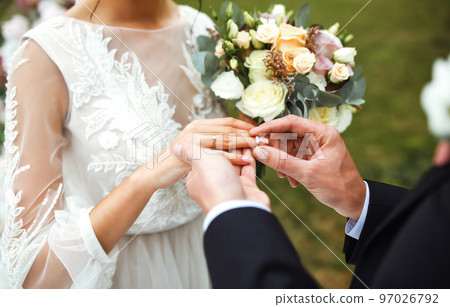 Wedding engagement rings. Groom put a ring on finger of his lovely wife. Concept wedding details. Happy family. 97026792