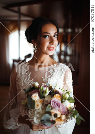 Beautiful bride with a wedding bouquet. Pretty woman with professional make up and hair style. Wedding day. Beautiful bride with a wedding bouquet. Pretty woman with professional make up and hair style. Wedding day. 97027012