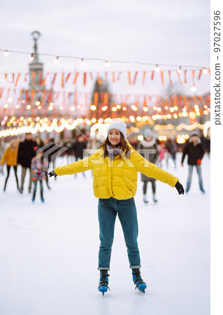 Beautiful woman have fun, active ice skating on the ice arena in the city in winter on Christmas Eve. Beautiful woman have fun, active ice skating on the ice arena in the city in winter on Christmas Eve. 97027596