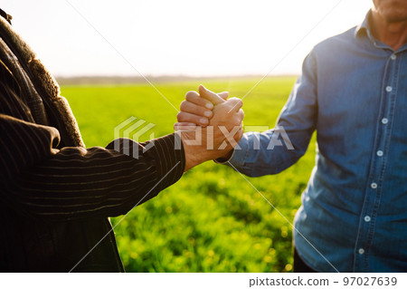 Handshake two farmer on the background of a wheat field at sunset. The concept of the agricultural business. 97027639