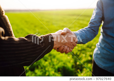 Handshake two farmer on the background of a wheat field at sunset. The concept of the agricultural business. 97027640
