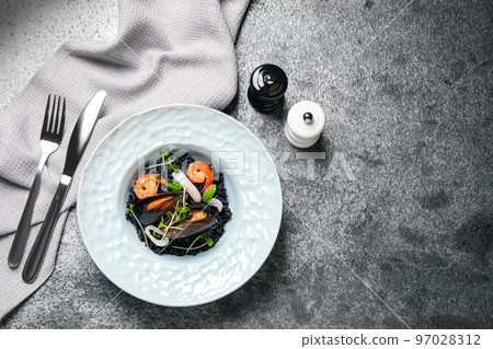 Delicious black risotto with seafood served on grey table, flat lay. Space for text Delicious black risotto with seafood served on grey table, flat lay. Space for text 97028312