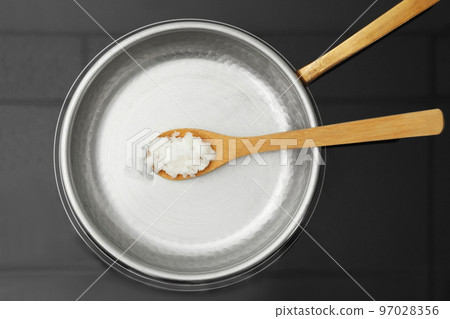 Frying pan with coconut oil and wooden spatula on induction stove, top view. Healthy cooking 97028356