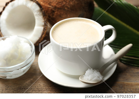 Delicious coffee with organic coconut oil on wooden table Delicious coffee with organic coconut oil on wooden table 97028357