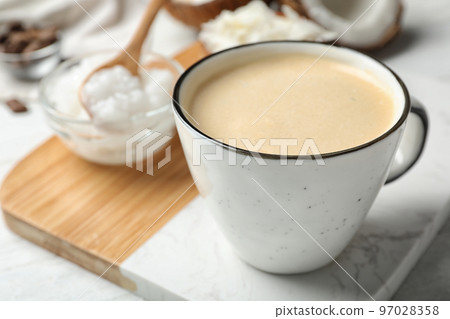 Delicious coffee with organic coconut oil on white wooden table Delicious coffee with organic coconut oil on white wooden table 97028358