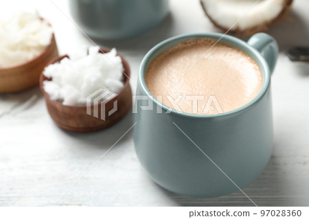 Delicious coffee with organic coconut oil on white wooden table Delicious coffee with organic coconut oil on white wooden table 97028360