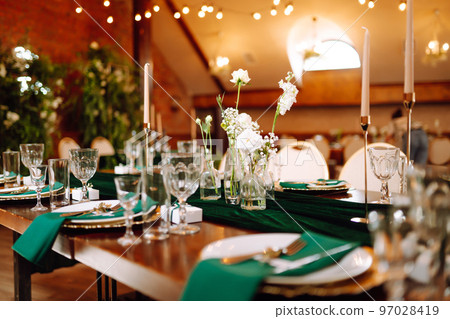 Banquet table in the restaurant, preparation before the banquet. The work of professional florists. 97028419