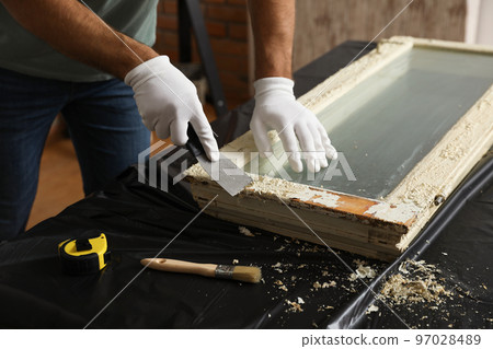 Man repairing old damaged window at table indoors, closeup Man repairing old damaged window at table indoors, closeup 97028489