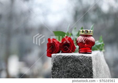 Red roses and candle on grey granite tombstone outdoors. Funeral ceremony Red roses and candle on grey granite tombstone outdoors. Funeral ceremony 97028561