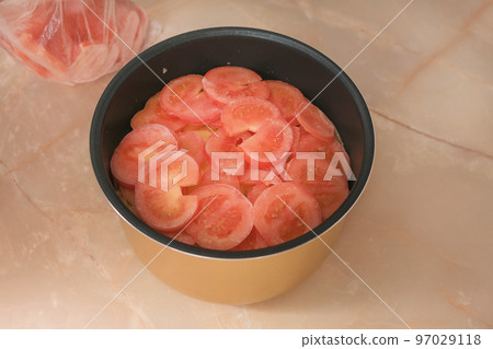 A man puts frozen tomatoes cut into thin slices in A man puts frozen tomatoes cut into thin slices in 97029118