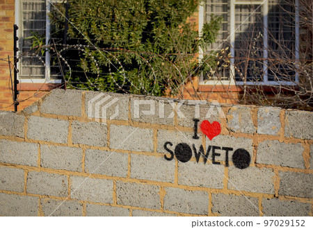 Inscription "I LOVE SOWETO" on concrete fence with barbed wire at the entrance to settlement on outskirts of Johannesburg. 97029152