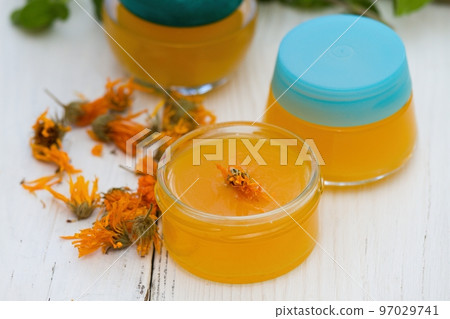 Making homemade organic calendula ointment, warm cream in small glasses 97029741