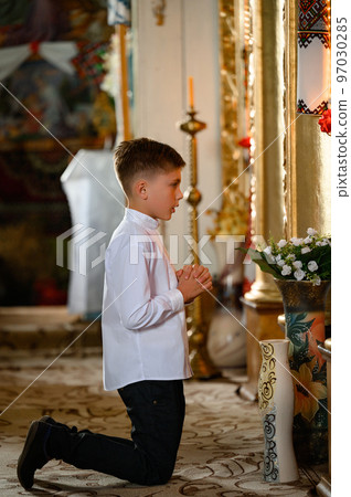 The boy is kneeling in prayer to God. The boy is kneeling in prayer to God. 97030285