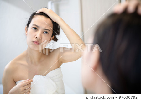 Problem skin. Concerned young asian women popping pimple on cheek while standing near mirror in bathroom. young asian women with acne Problem skin. Concerned young asian women popping pimple on cheek while standing near mirror in bathroom. young asian women with acne 97030792