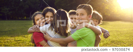 Group of happy little children hugging each other while having fun in sunny summer park Group of happy little children hugging each other while having fun in sunny summer park 97030874