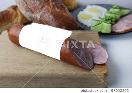 still life made of ham sausage in a loaf on a wooden tray board. A loaf of sausage and sliced pieces of sausage close-up. meat food still life made of ham sausage in a loaf on a wooden tray board. A loaf of sausage and sliced pieces of sausage close-up. meat food 97032295
