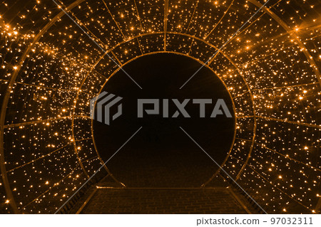 tunnel and illuminations of orange yellow white on a black dark background. New Year's Eve Christmas. Photoona festive atmosphere 97032311
