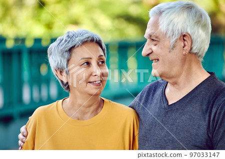 Optimistic attractive multiracial elderly 60s couple outdoors 97033147