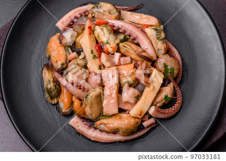 Delicious pickled seafood salad or cocktail on a black plate Delicious pickled seafood salad or cocktail on a black plate 97033181