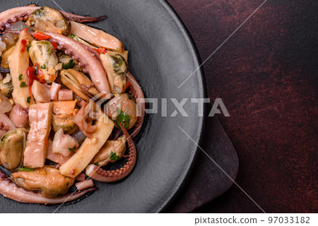Delicious pickled seafood salad or cocktail on a black plate Delicious pickled seafood salad or cocktail on a black plate 97033182