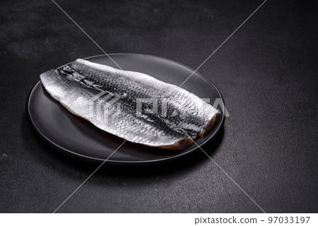 Marinated fillet with spices and herbs of sea herring on a black plate Marinated fillet with spices and herbs of sea herring on a black plate 97033197