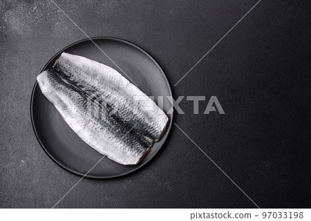 Marinated fillet with spices and herbs of sea herring on a black plate 97033198