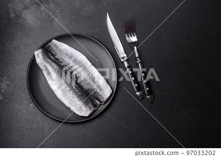 Marinated fillet with spices and herbs of sea herring on a black plate Marinated fillet with spices and herbs of sea herring on a black plate 97033202