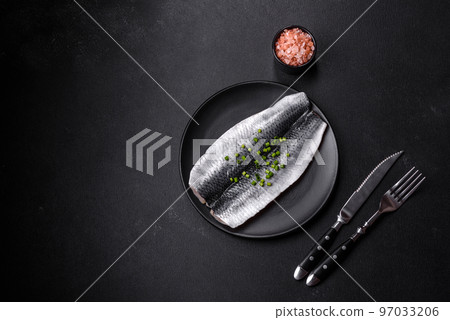 Marinated fillet with spices and herbs of sea herring on a black plate Marinated fillet with spices and herbs of sea herring on a black plate 97033206