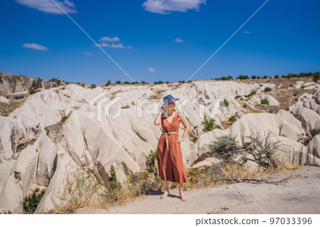 Young woman exploring valley with rock formations and fairy caves near Goreme in Cappadocia Turkey 97033396