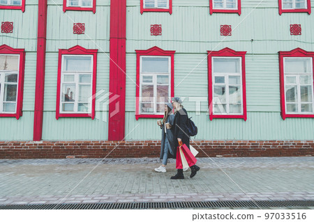 Young shopaholic friends women friends walking and carry shopping bags in the street spring or winter city with happy and smiling - purchase and free time concept 97033516