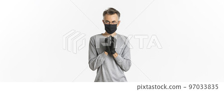 Concept of covid-19, social distancing and lifestyle. Image of cunning middle-aged man in black medical mask and gloves, making plan, scheming something bad, standing over white background 97033835