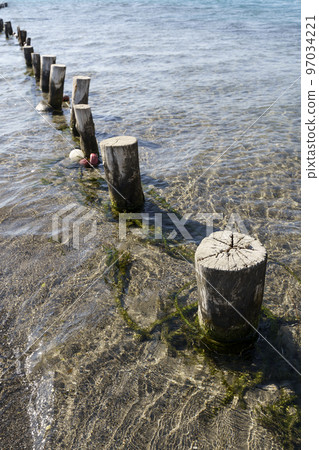Sea coast and beach with wooden poles and clean clear sea water Sea coast and beach with wooden poles and clean clear sea water 97034221