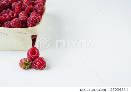 Raspberries in and out of the basket. Ripe crimson berries close-up, space for text, white background 97034234