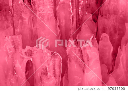 Blue ice and icicles on the rocks of Ogoy island, Baikal lake, Siberia, Russia. Abstract winter nature background. Toned image in trendy magenta color of year 2023. 97035500