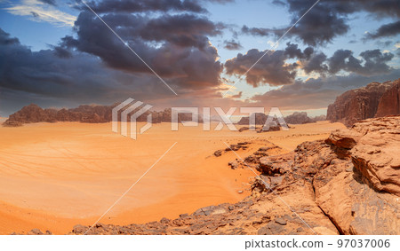 Red sands, mountains, dramatic sky and marthian landscape panorama of Wadi Rum desert, Jordan Red sands, mountains, dramatic sky and marthian landscape panorama of Wadi Rum desert, Jordan 97037006