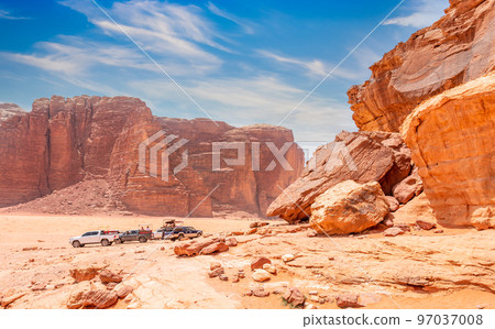 Red stones and rocks of Wadi Rum desert with cars in the background, Jordan Red stones and rocks of Wadi Rum desert with cars in the background, Jordan 97037008