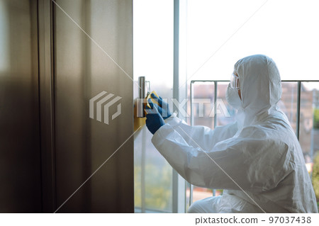 Cleaning and disinfection of the elevator to prevent COVID-19. Worker wearing protective suit sprays. 97037438