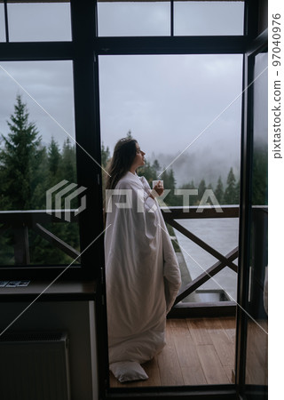 Woman drinking tea on cozy balcony of a country house. 97040976