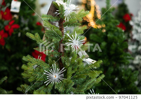 Elements of Christmas tree with white snowflakes in the decorated hall in the store, close-up 97041125