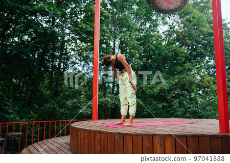 A young woman in doing yoga in the yard 97041888