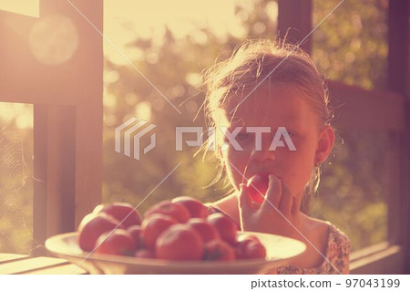 Little girl sitting on porch in summer. Tomatoes on plate. Dreamy and romantic image. Summer and happy childhood concept Little girl sitting on porch in summer. Tomatoes on plate. Dreamy and romantic image. Summer and happy childhood concept 97043199
