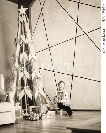 little girl sitting near a stylized Christmas tree. black and white photo 97049540