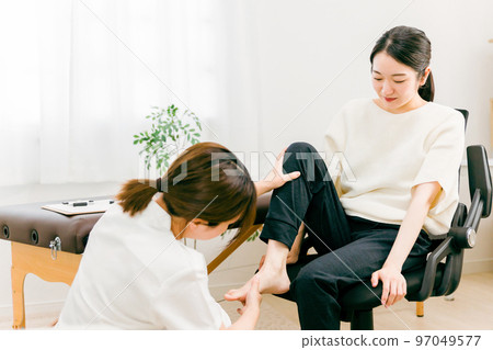 An Asian woman and a physical therapist receiving treatment for sprains, flat feet, and bunions at a hospital/orthopedic surgery 97049577