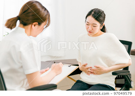 一名女醫生/護士在醫院內科檢查/採訪/諮詢患有胃潰瘍/腹痛的患者 97049579